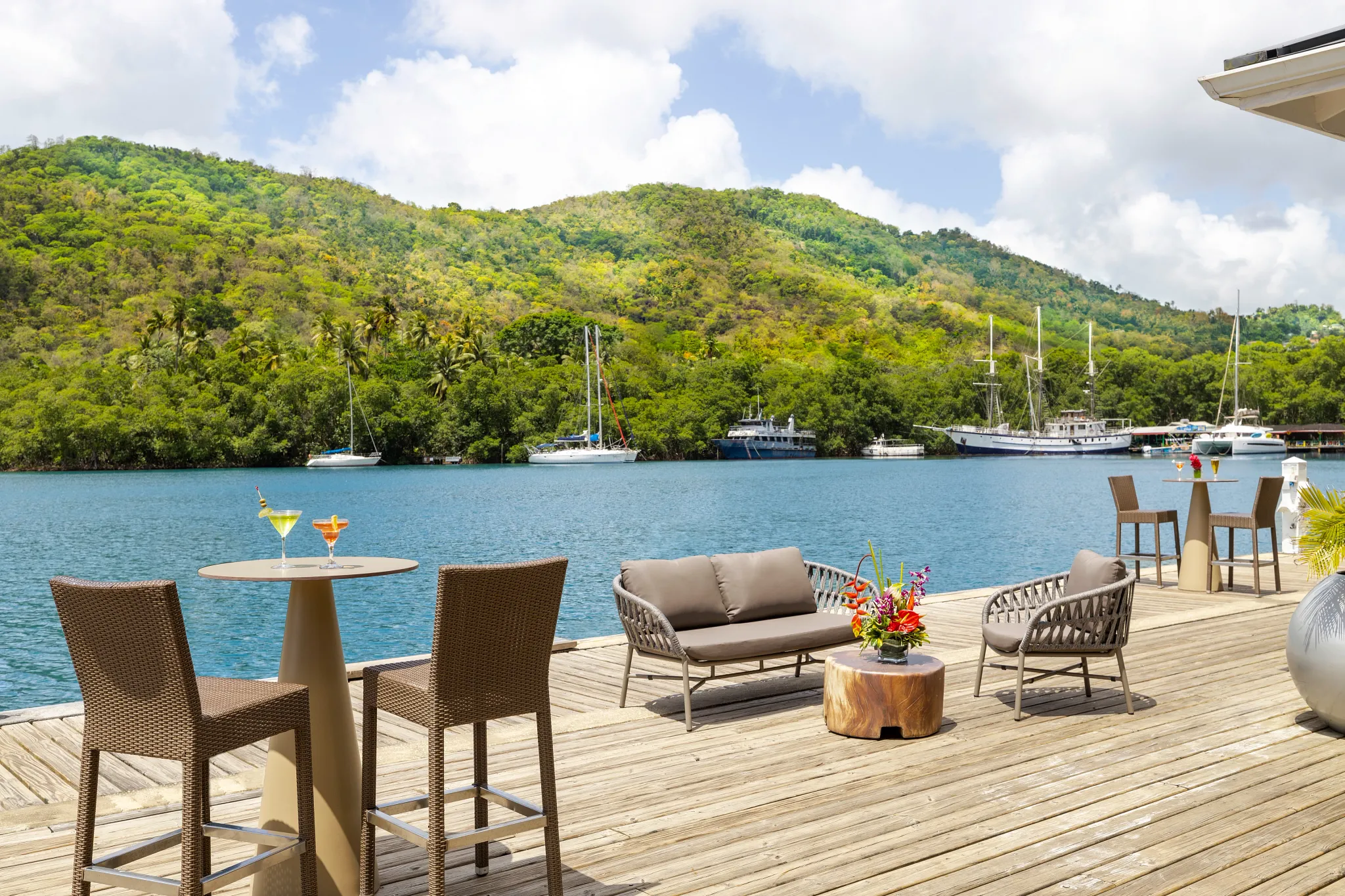 Hurricane Hole Bar at Zoëtry Marigot Bay St. Lucia featuring waterfront pub seating with marina and lush hillside views.