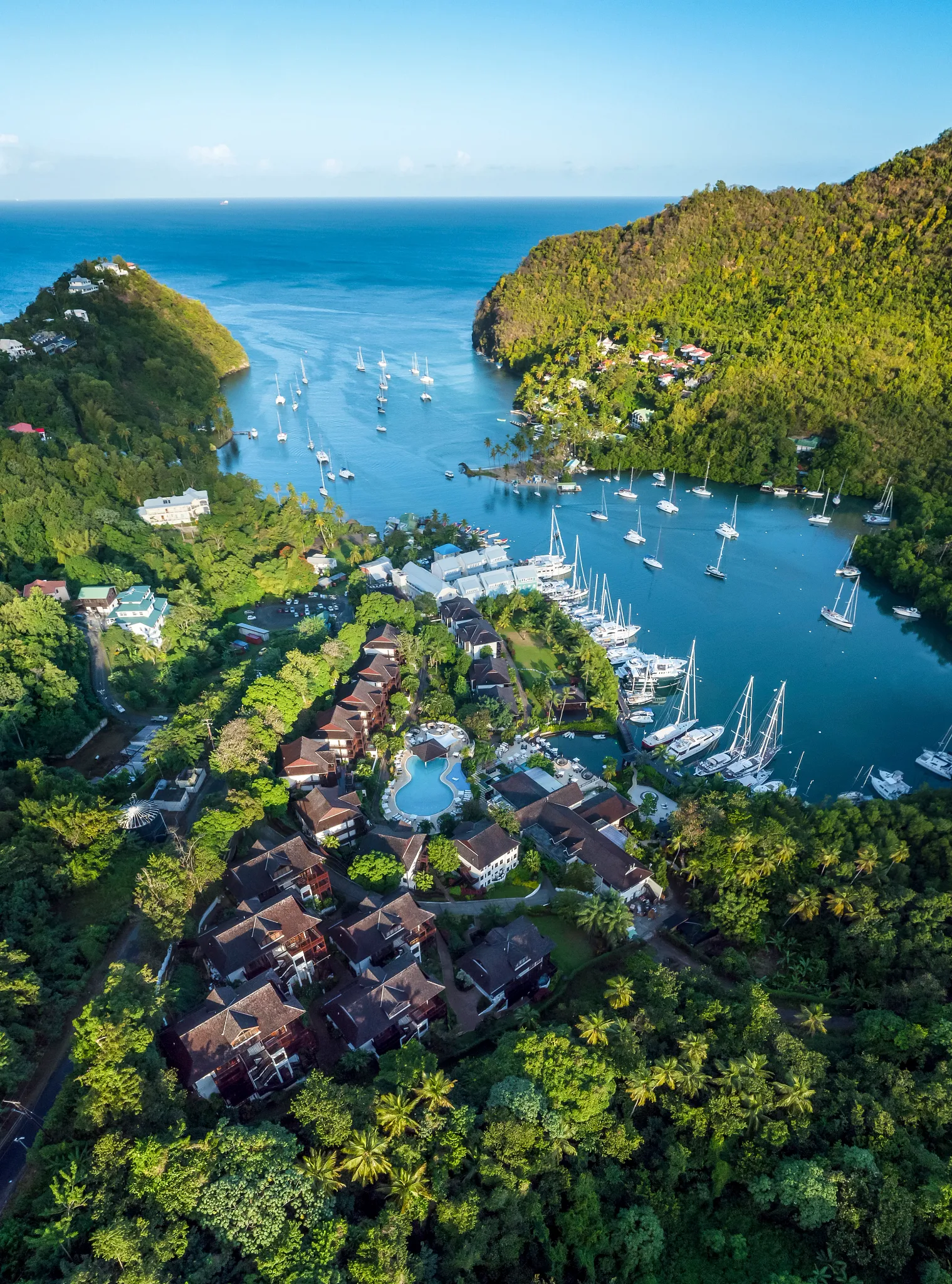 Aerial view of Zoëtry Marigot Bay St. Lucia nestled between lush green hills and the turquoise marina filled with luxury yachts.