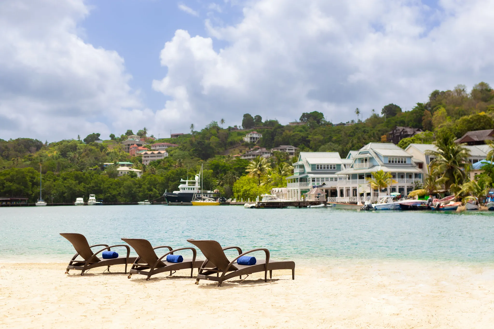 Lounge chairs set on a sandy beach near Zoëtry Marigot Bay St. Lucia overlooking calm Caribbean waters.
