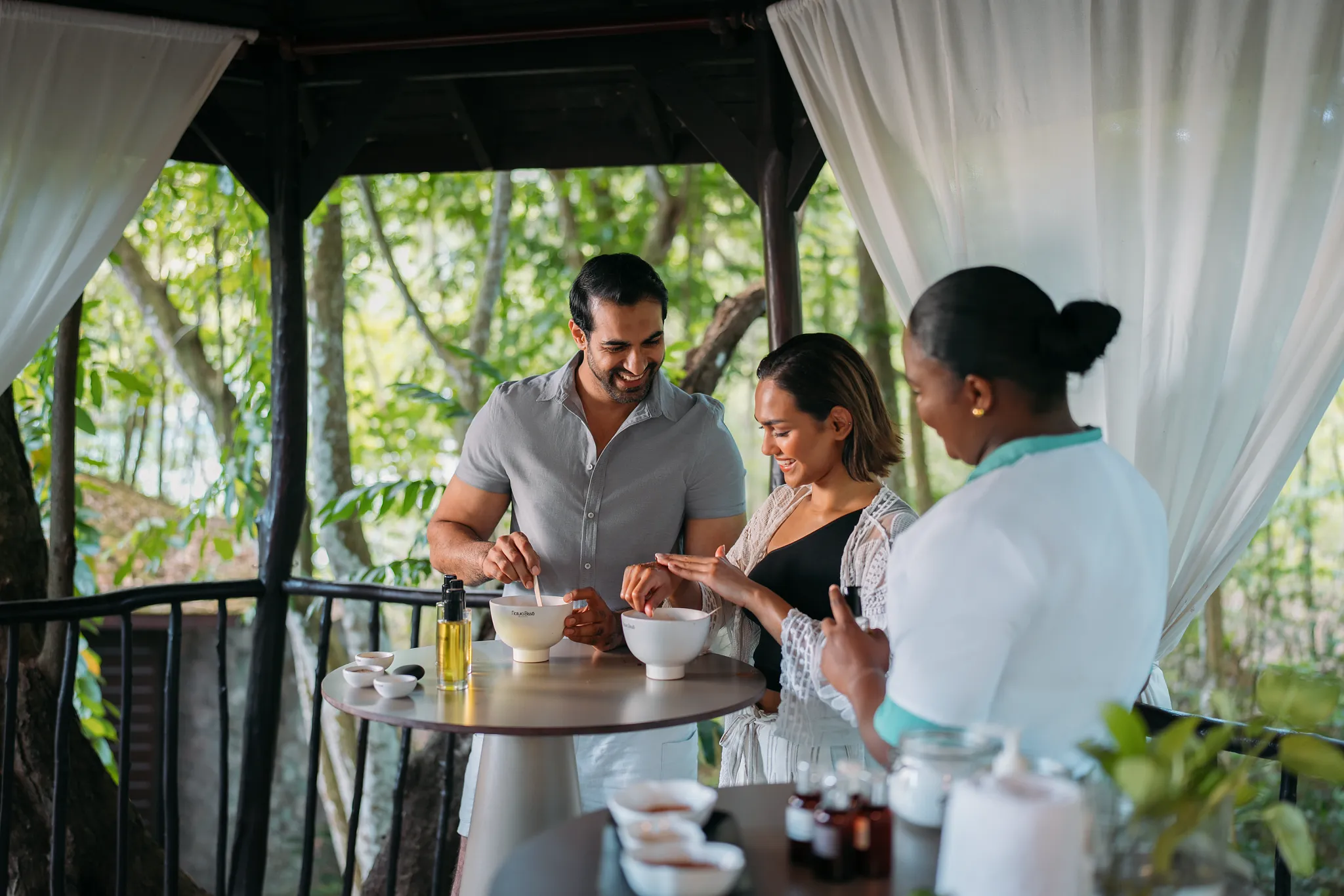 Couple enjoying a hands-on body scrub class at Zoëtry Marigot Bay St. Lucia, learning natural spa rituals in a tropical open-air setting.