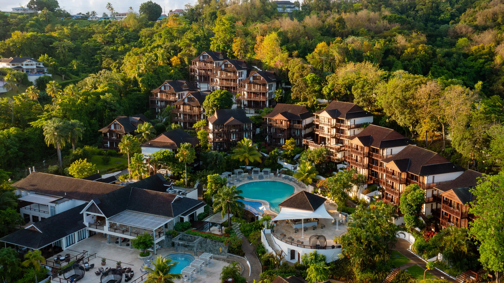 Zoëtry Marigot Bay St. Lucia hillside resort view featuring tropical gardens, infinity-style pools, and wooden villa buildings.
