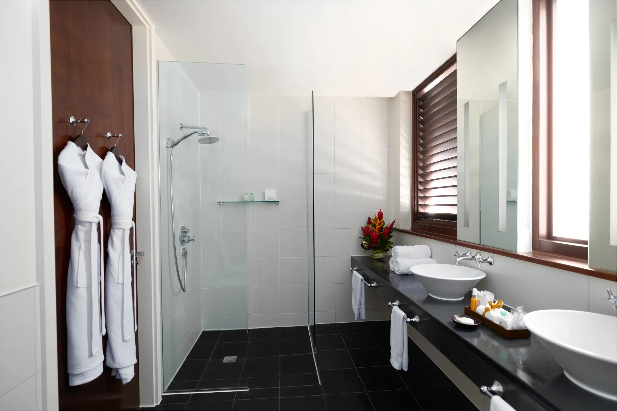Modern bathroom with double vanities and walk-in shower in Junior Suite Garden View at Zoëtry Marigot Bay.