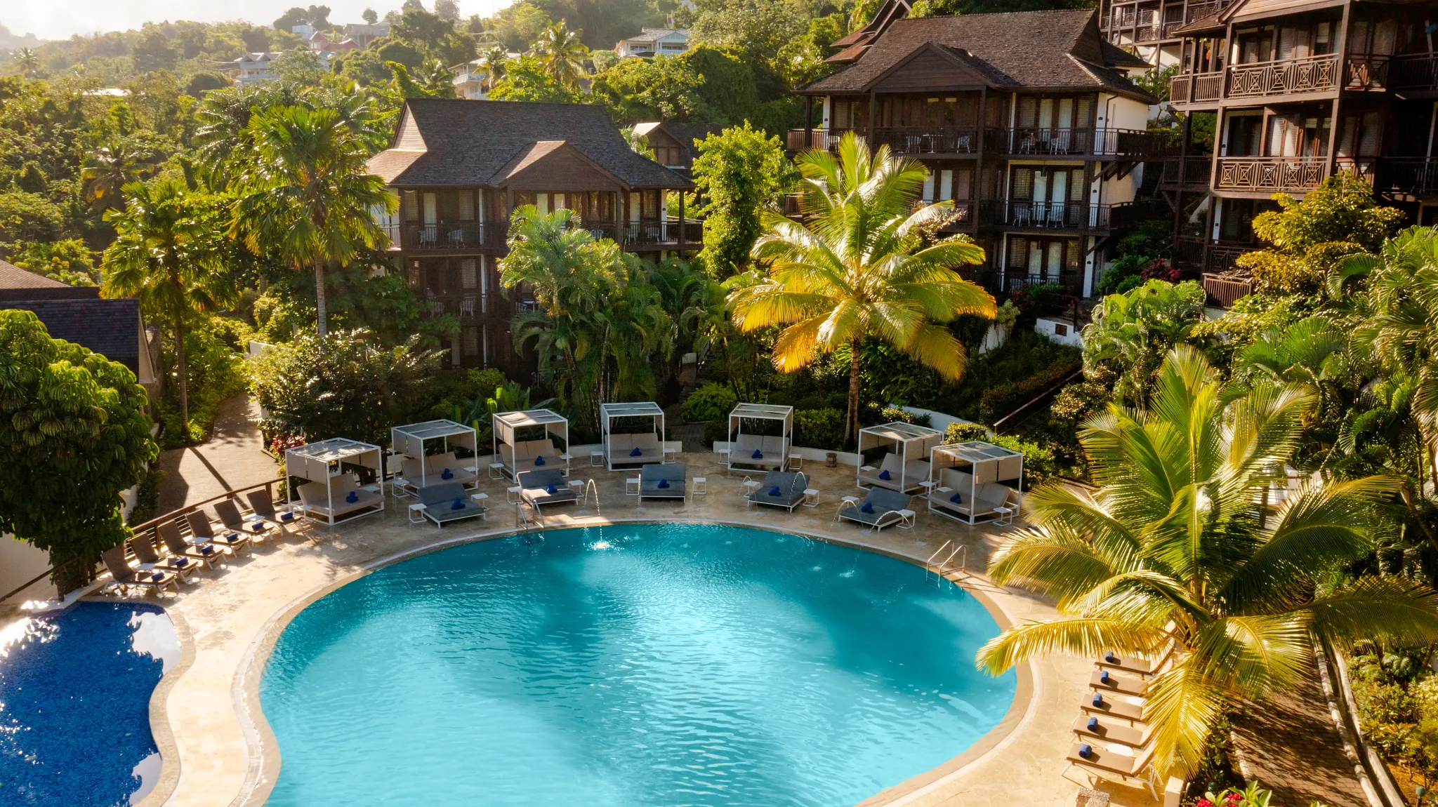 Main pool with private cabanas and palm trees at Zoëtry Marigot Bay St. Lucia.