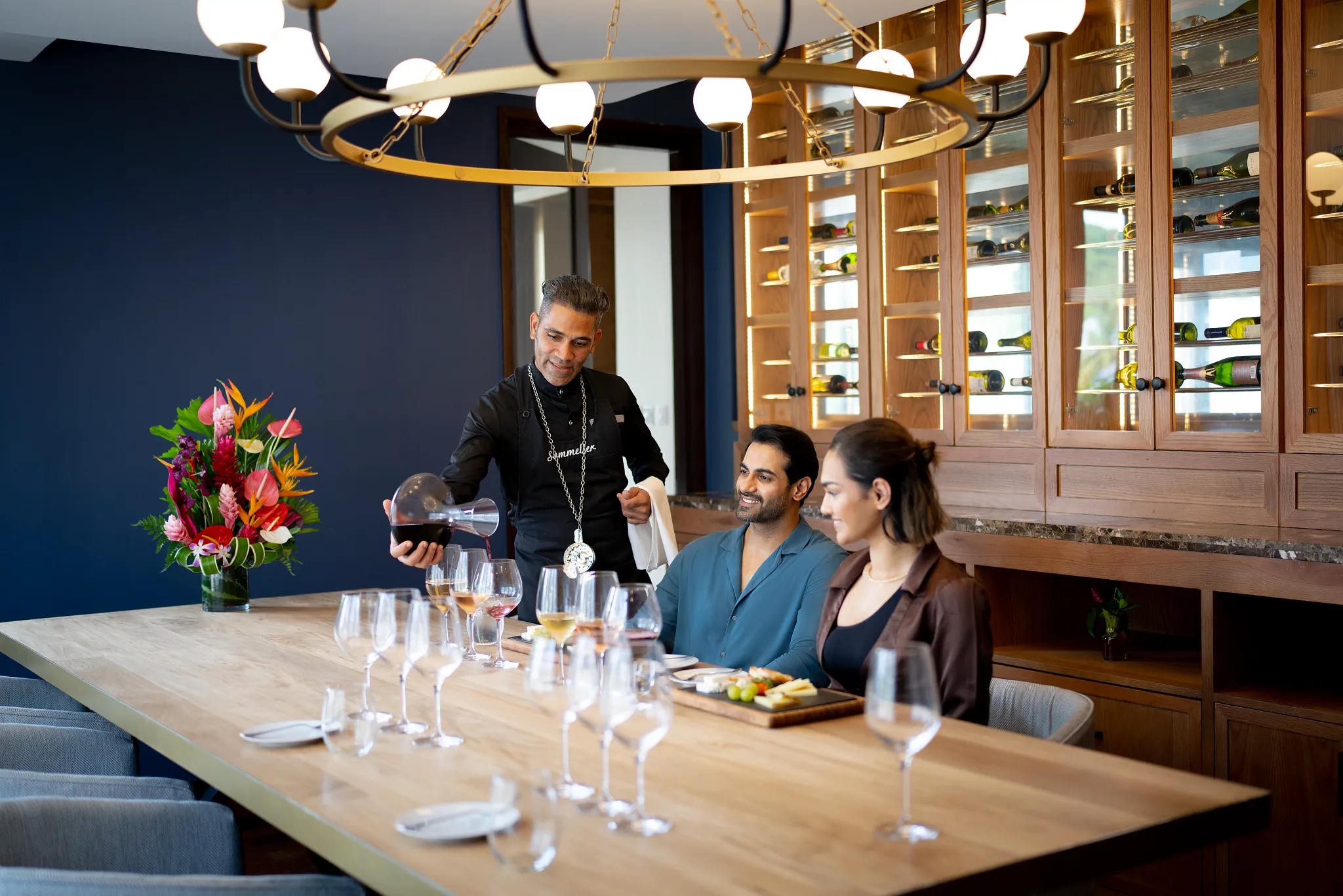 Sommelier pouring red wine for a couple during a wine tasting experience at Zoëtry Marigot Bay St. Lucia.