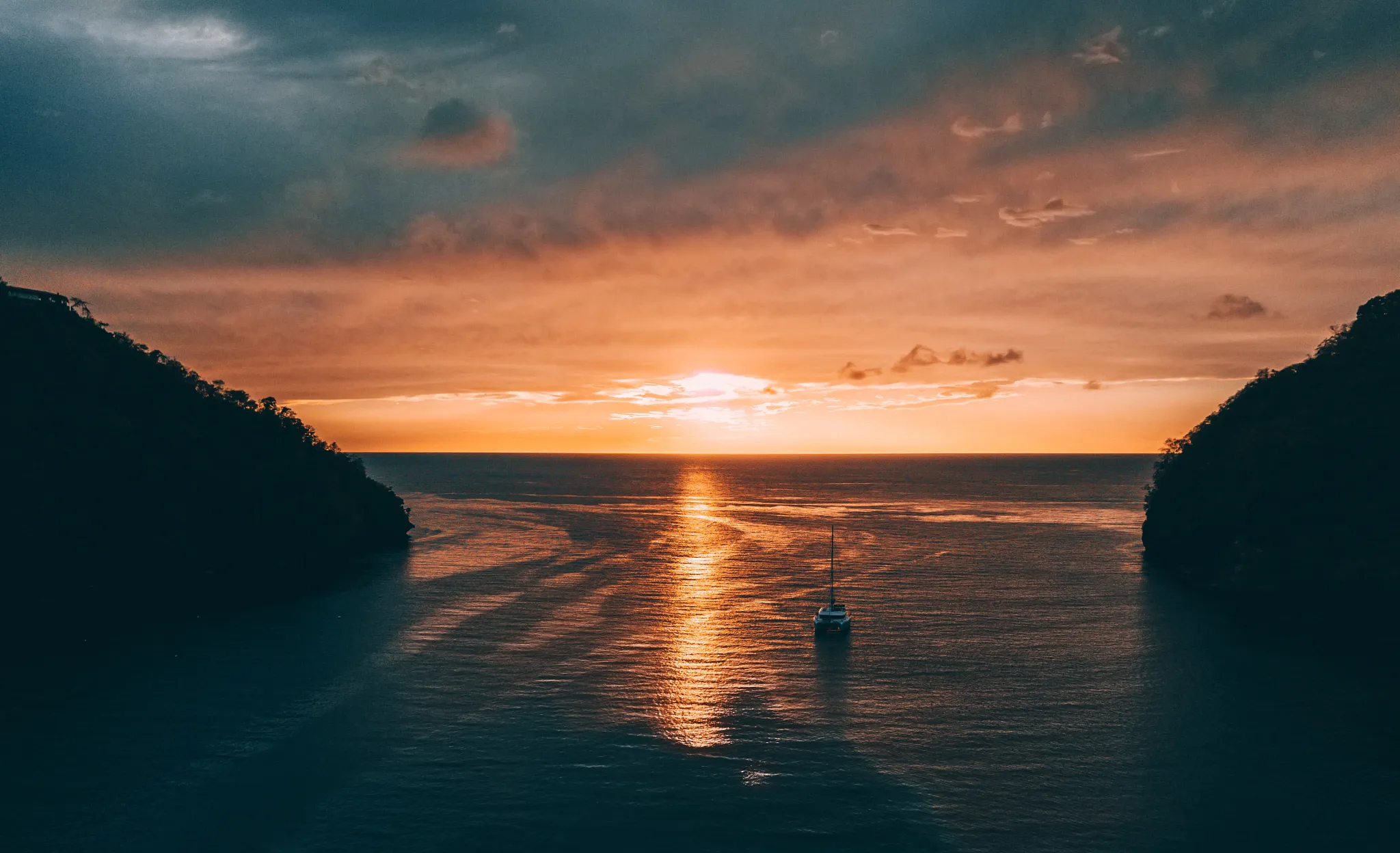 Sunset view at the entrance of Marigot Bay near Zoëtry Marigot Bay St. Lucia with sailboats anchored in golden light.